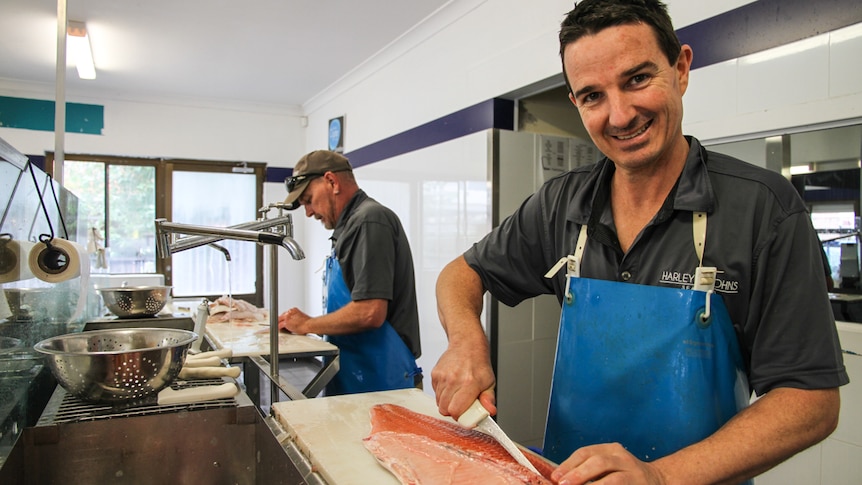 two men prepare fresh fish in their shop