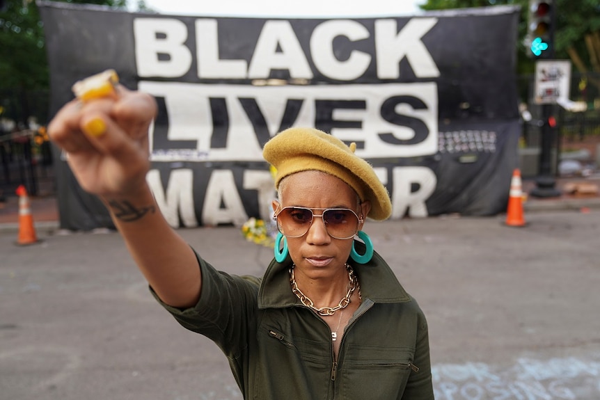 Tee Wright, from Washington, raises a fist in front of a Black Lives Matter banner across from the White House in Washington.