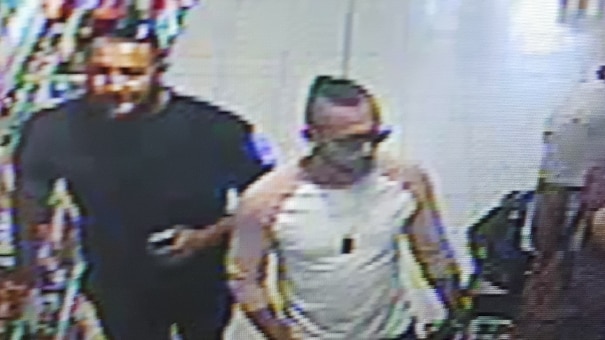 Three men in their mid twenties-thirties walk through a dollar store on CCTV footage