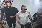 Three men in their mid twenties-thirties walk through a dollar store on CCTV footage