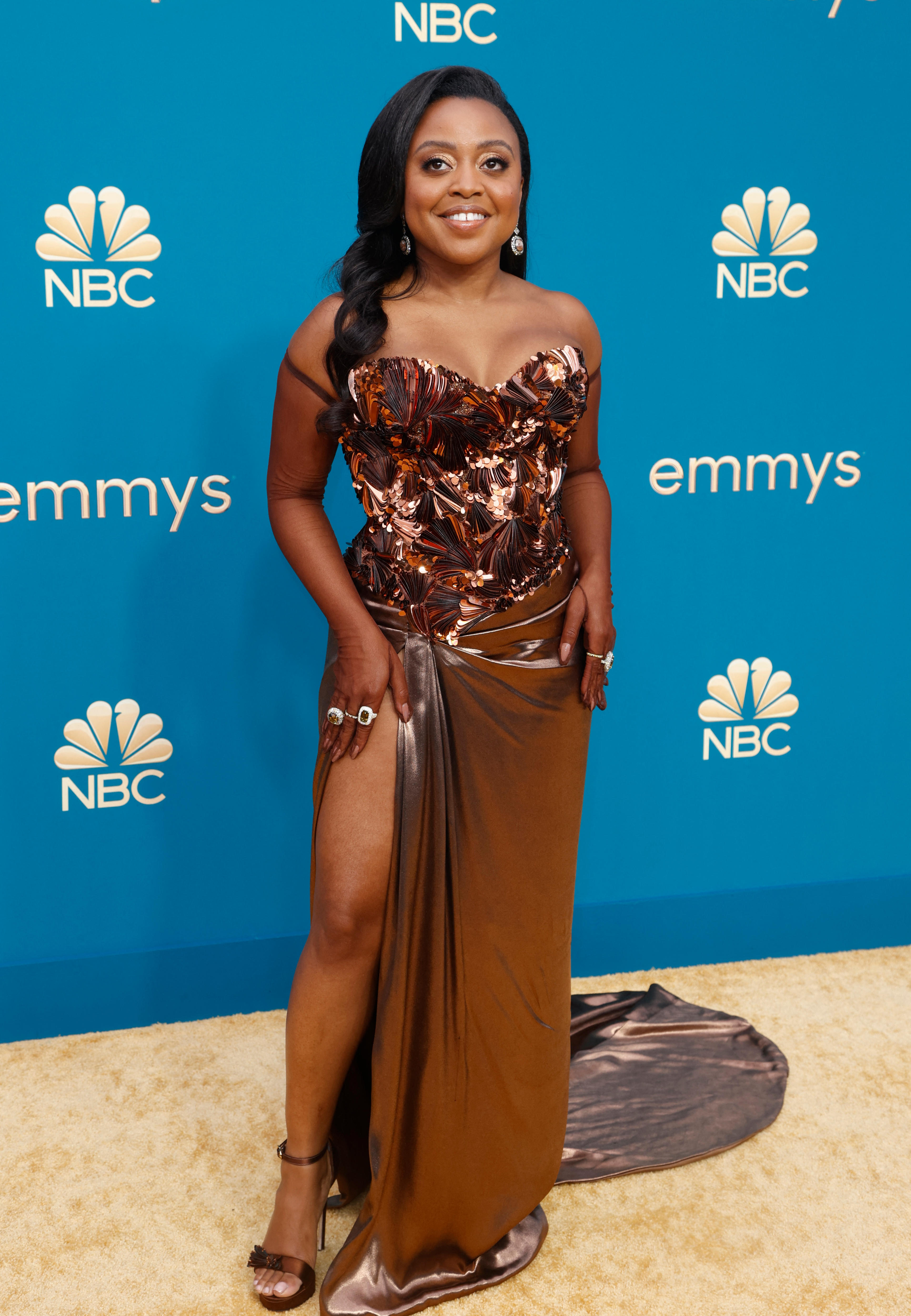 Quinta Brunson wearing a bronz strapless gown with a silky long skirt and a beaded, embellished bodice. 
