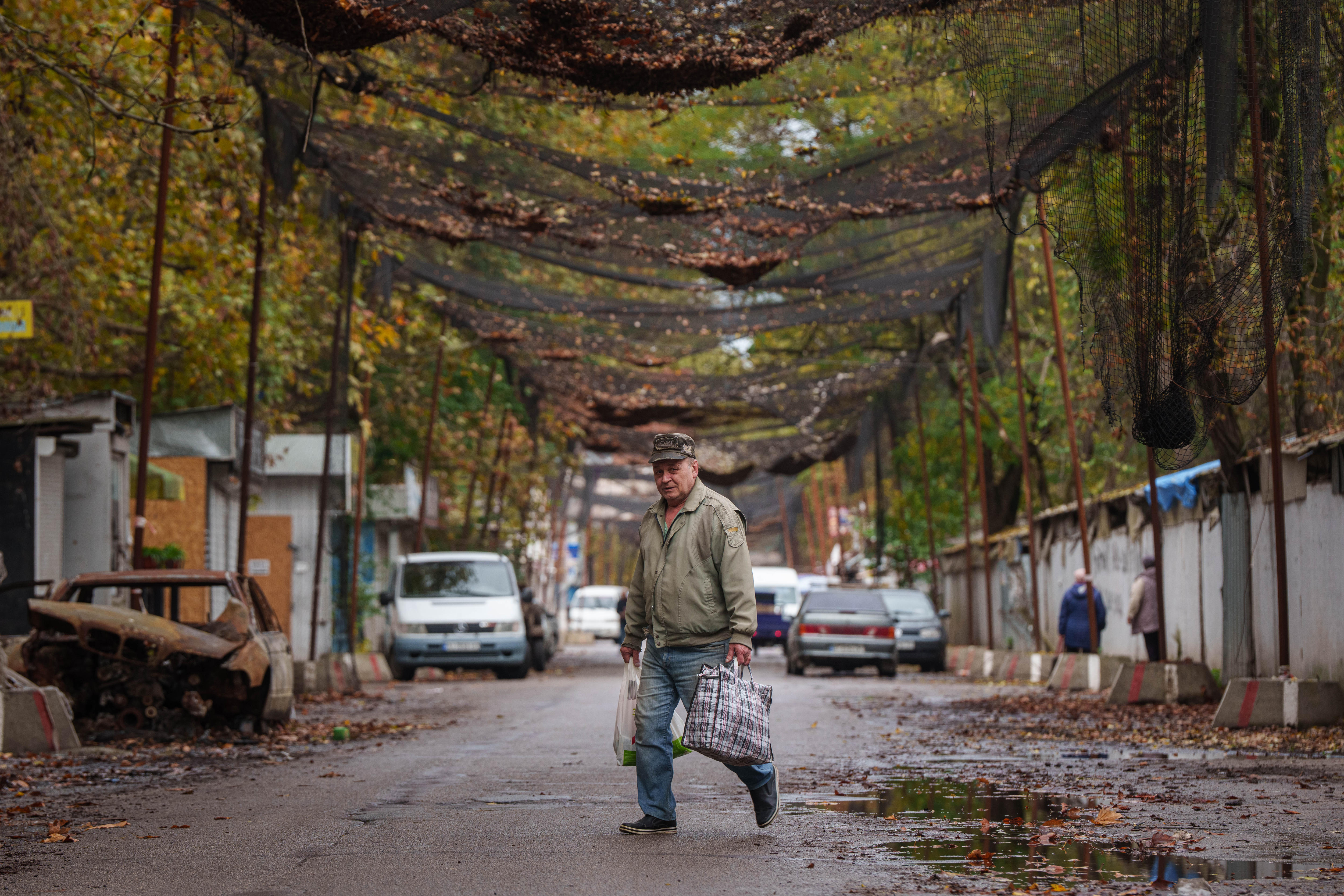Man carries shopping bags as he walks across street in European town
