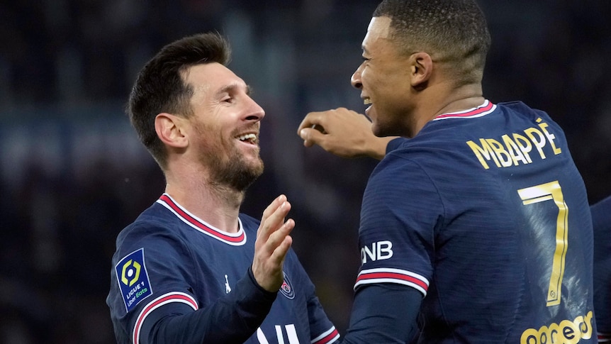 Lionel Messi and Kylian Mbappé lean in to hug each other while smiling after mbappe scored a goal for PSG