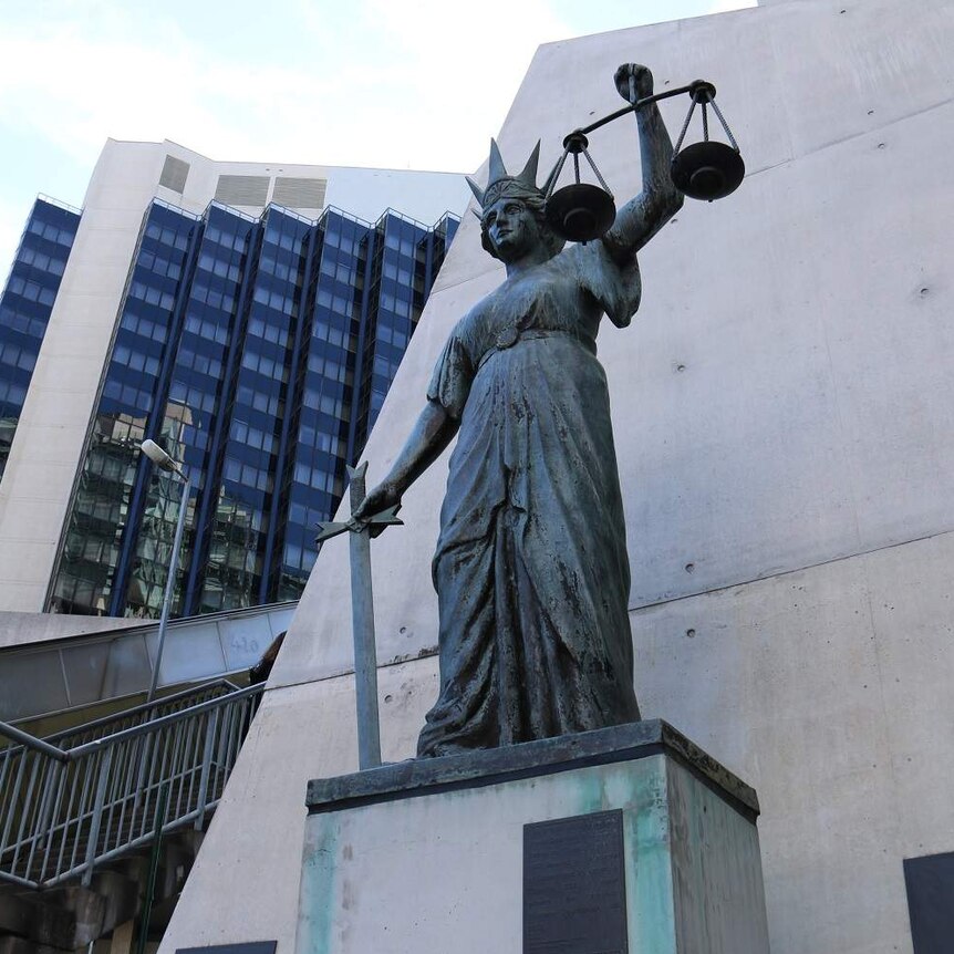 Scales of Justice statue of a woman holding a set of scales and a sword while wearing a crown outside Brisbane's Supreme Court.