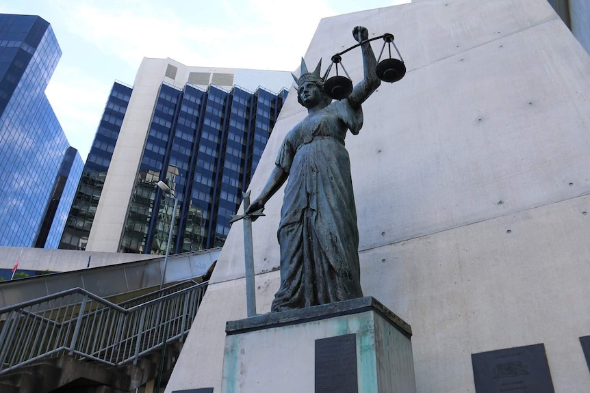 Scales of Justice statue of a woman holding a set of scales and a sword while wearing a crown outside Brisbane's Supreme Court.