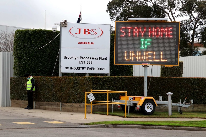 A sign outside JBS says 'stay home if unwell'.