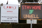 A sign outside JBS says 'stay home if unwell'.