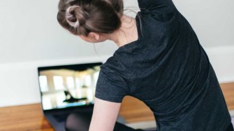 Woman does yoga via video instruction