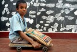 A 10-year-old Indian polio victim moves his wooden plank with wheels.