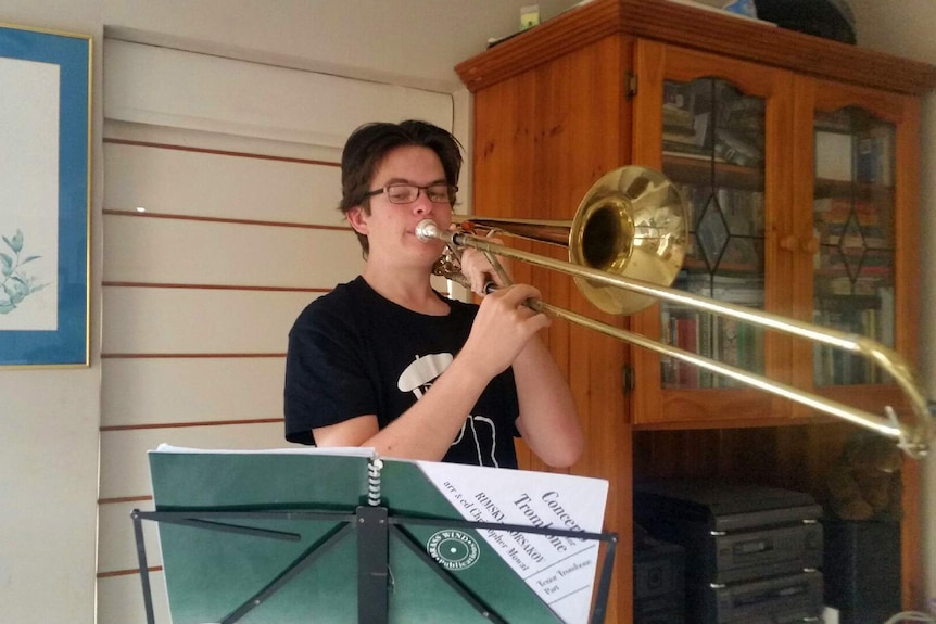 Zac Bonham plays a trombone in his home.