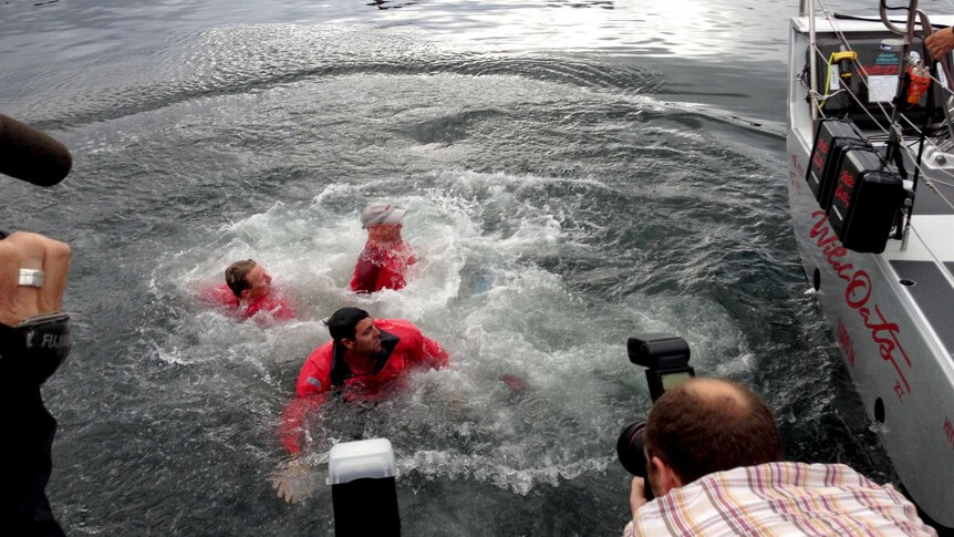Mark Richards, bottom, and other crew members swim in the water at Constitution Dock.