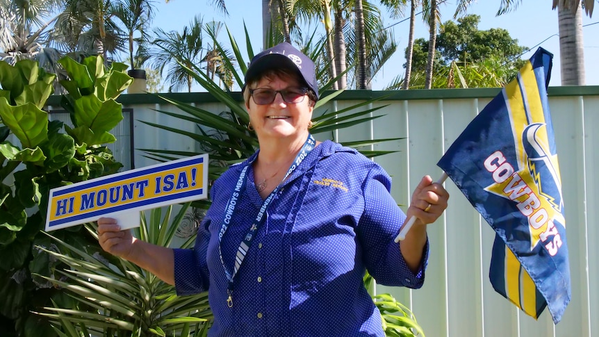 A cowboys fan smiling with cowboys memorabilia in front of a garden