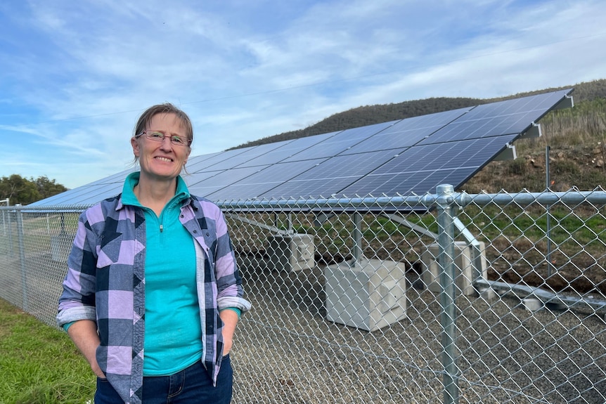 A woman stands in front of solar panels