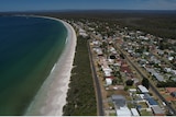 Aerial shot of coastal village with bush-land behind