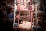 A man works on a jarrah dining chair in a workshop