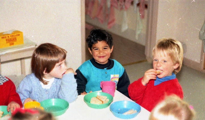 Marc, centre, sits in a classroom at the corner of a table between other children in the 90s.