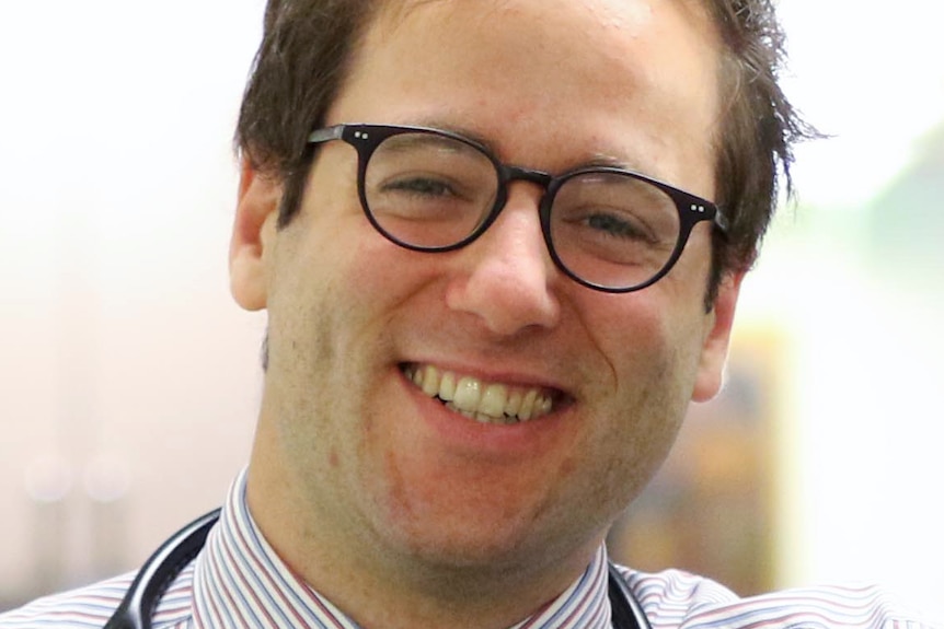 A man with a stethoscope around his neck smiles