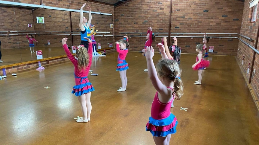 A socially distanced ballet class in a brick hall.