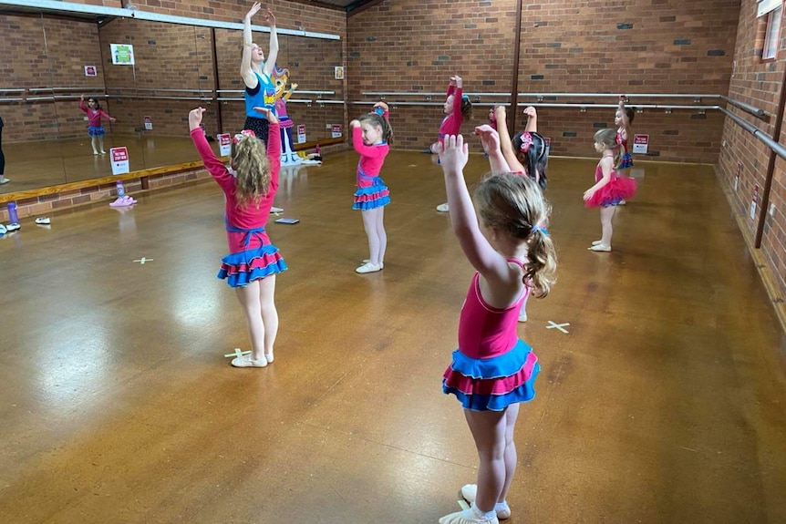 A socially distanced ballet class in a brick hall.