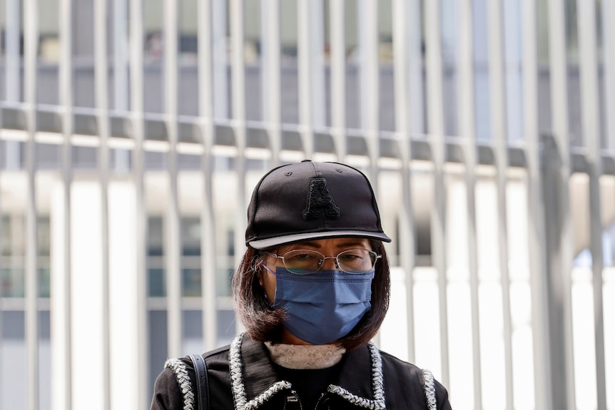 A woman in a baseball cap and COVID mask