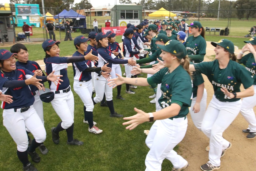 Two women's baseball teams line up to shake hands.