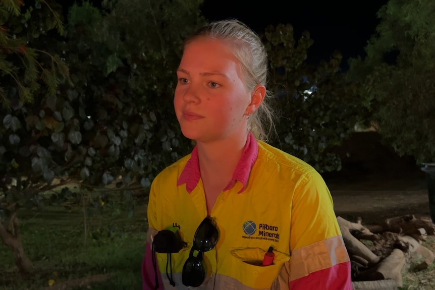 Young woman sits at night in high-vis shirt. 