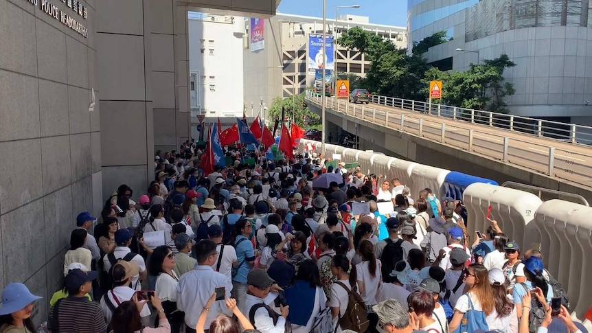 You look down at a crowd of hundreds as they are wedged between barricades and the walls of the Hong Kong police headquarters.
