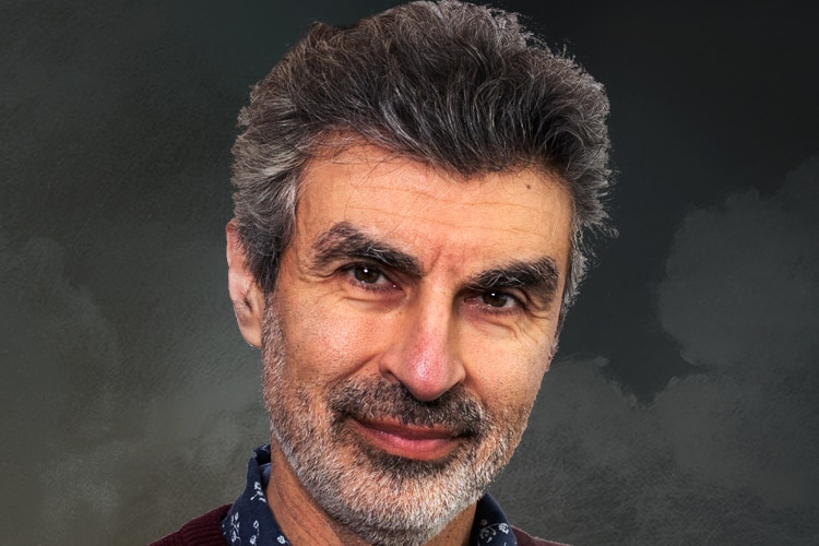 A professional portrait of a middle-aged man against a mottled grey background.