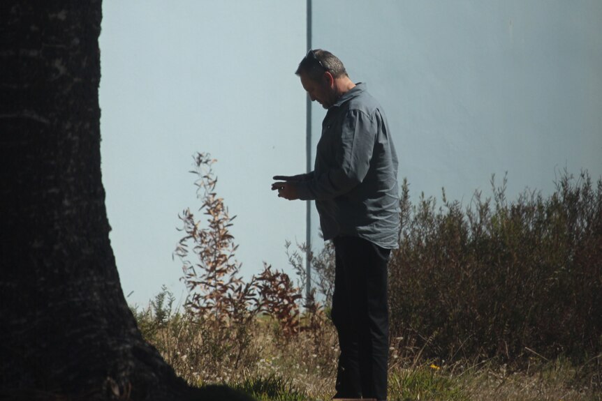 A middle-aged man on a phone awaiting his court appearance