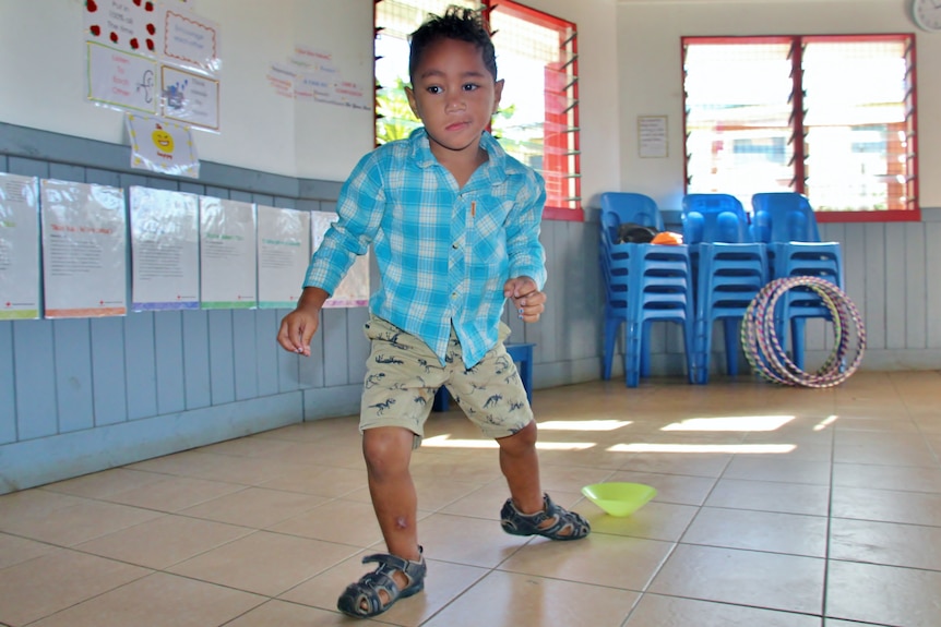 A young boy running inside a school hall