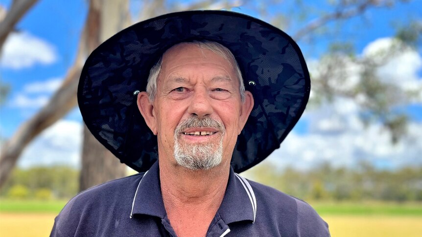 A white man in his 60s, wearing a sun hat, with a grey goatee and short white hair. 