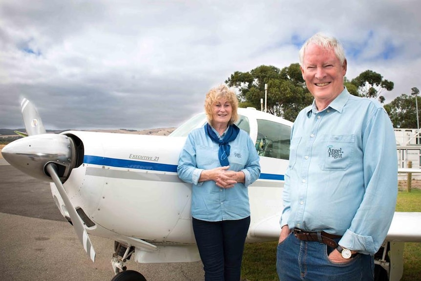 Two people stand in front of a light aircraft