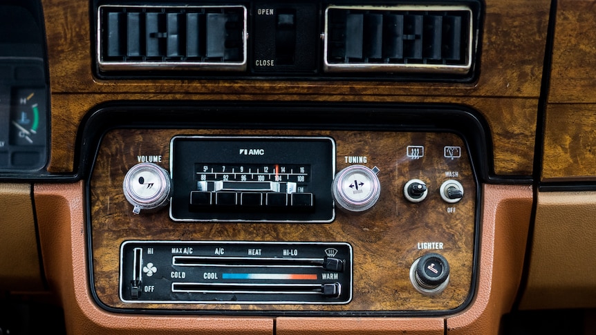 The console is brown with a fake wood plastic panel and vintage buttons and controls for the radio and airconditioning