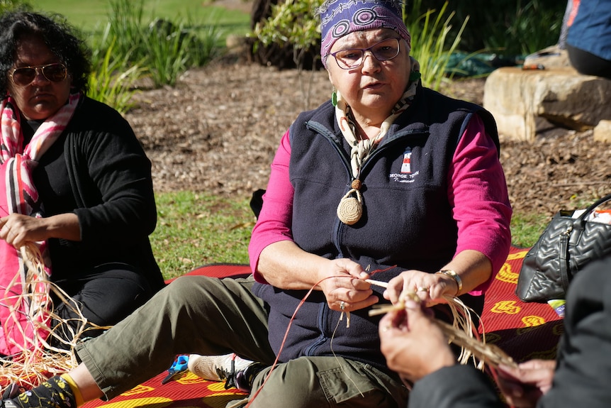 women sit in a circle, weaving