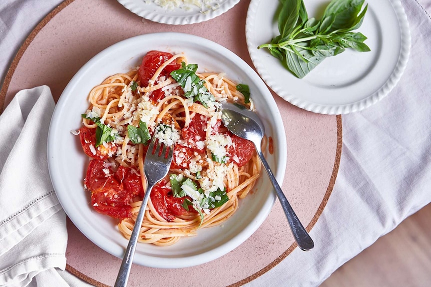 A bowl of linguini with slow roasted tomato sauce topped with basil and parmesan cheese, for a weeknight or special dinner.