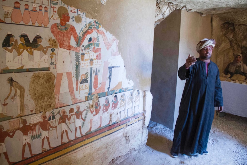 A guard stands by the funeral mural inside the tomb.