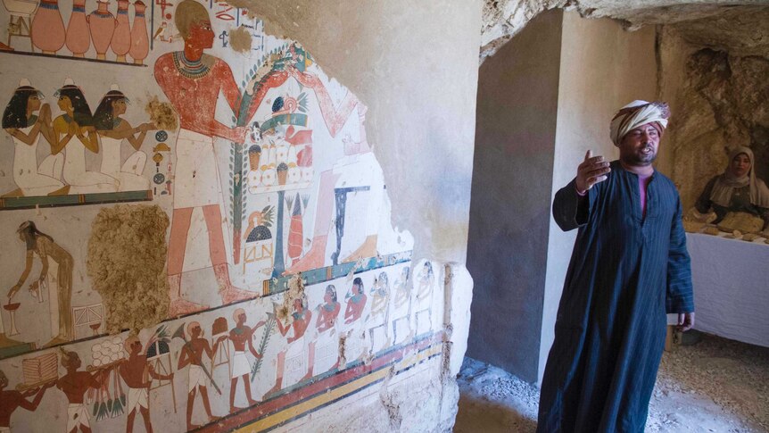 A guard stands by the funeral mural inside the tomb.