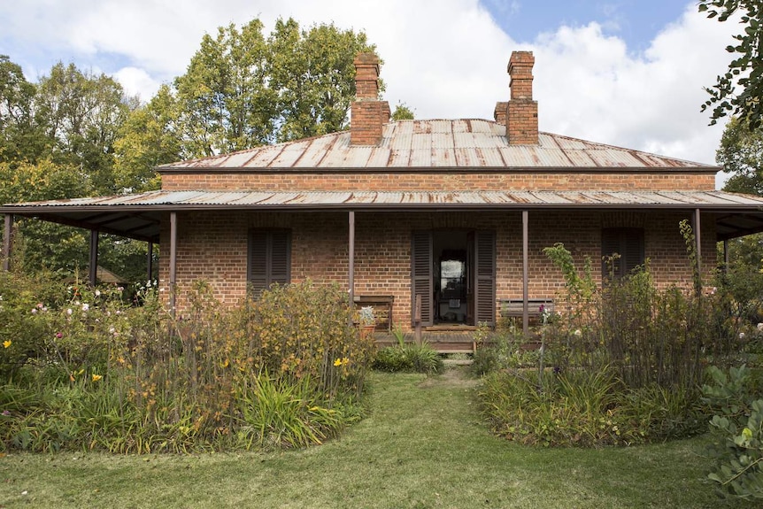 Photo of old brick house with green garden in front.