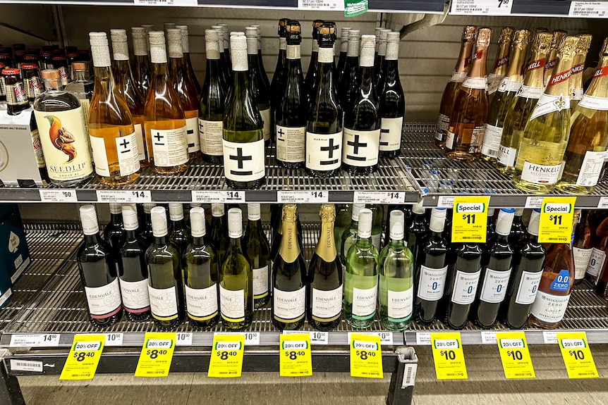Estantes de supermercados con docenas de vinos sin alcohol y pegatinas de venta de color amarillo brillante