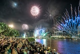 Hundreds of people standing in front of river watching fireworks