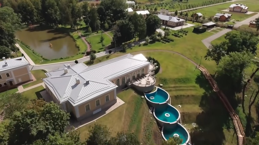 An aerial shot shows a lavish property with a three-tier pool cascading from a patio