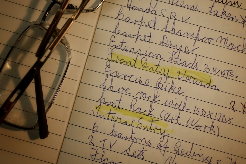 A pair of spectacles sit on a handwritten list of items.