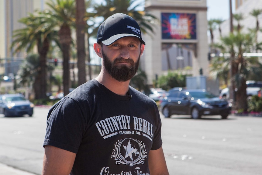 Man wearing a black T-shirt and cap stands on the Las Vegas strip.