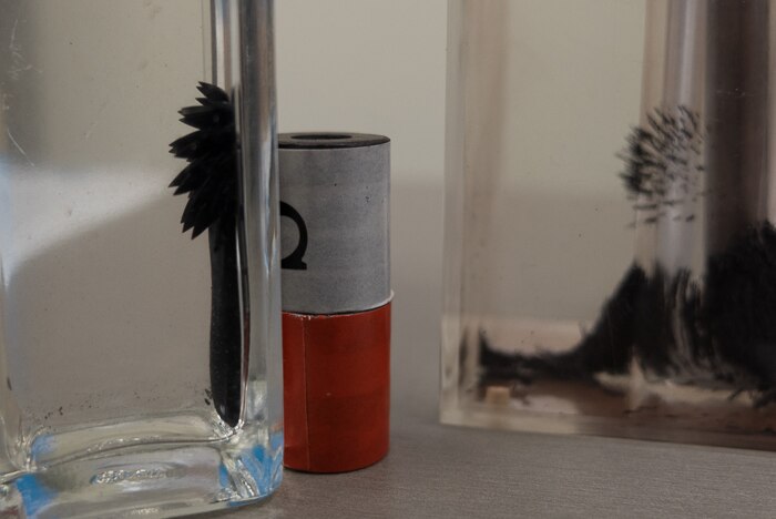 Containers with ferrofluid and iron shavings react to magnetic forces.