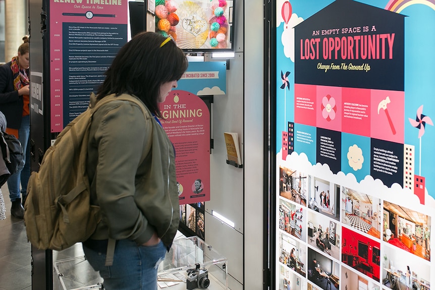 A woman at Renew In A Box exhibition looks at a panel saying 'an empty space is a lost opportunity'