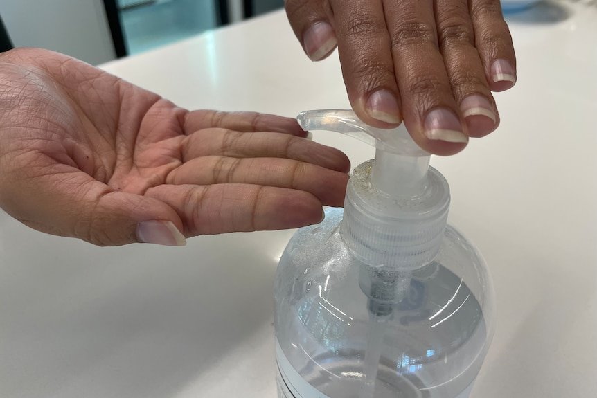 A person squeezing sanitiser on their hands.