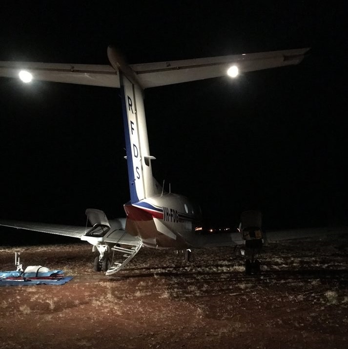 The tail of a Royal Flying Doctor Service aircraft lit up at night in a remote location
