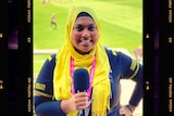 A woman wearing a hijab holds a microphone and smiles.