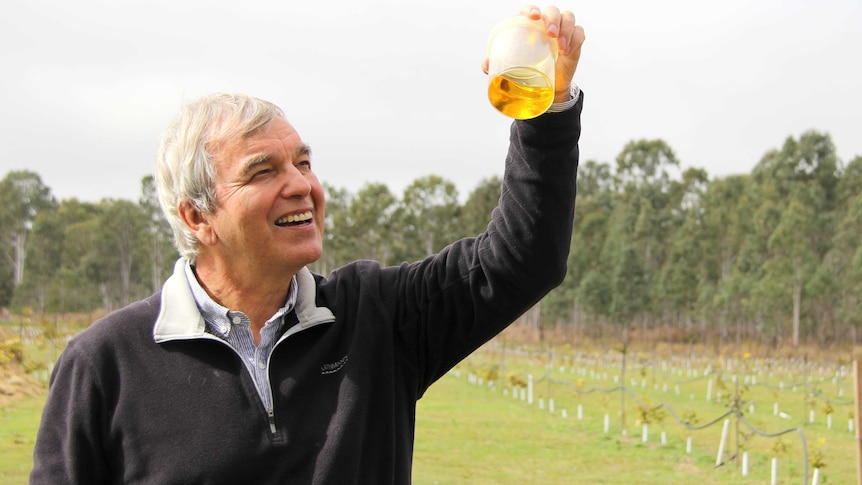 Professor Peter Gresshoff at the sewage treatment plant with a jar of oil from the pongamia seed.