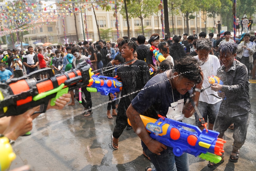 People shoot each other with water guns. 